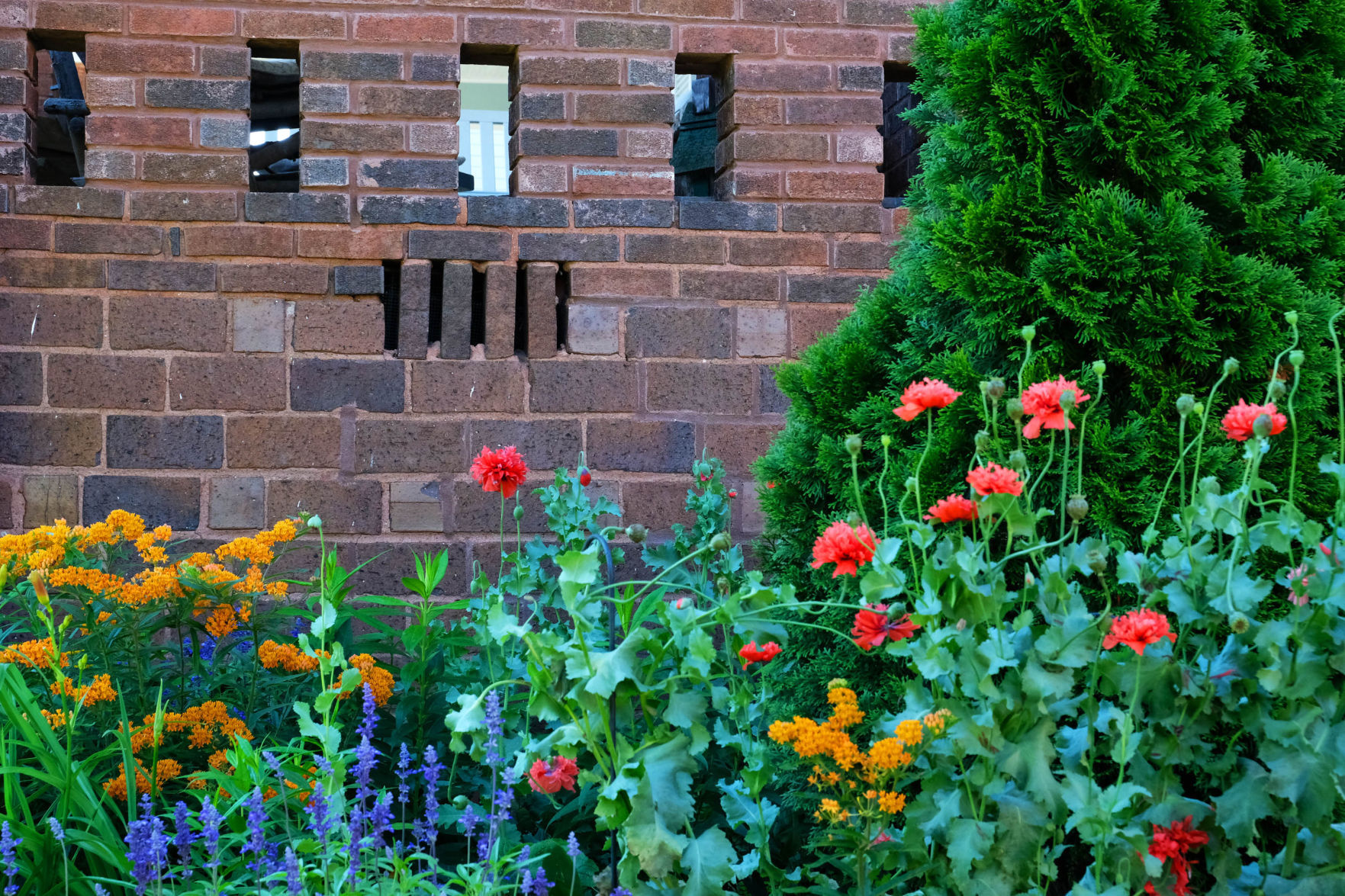 Looking out the windows of the back porch, an impressive cottage garden opens before you with peonies, hostas, roses and herbs, weaving around the red brick walkways.